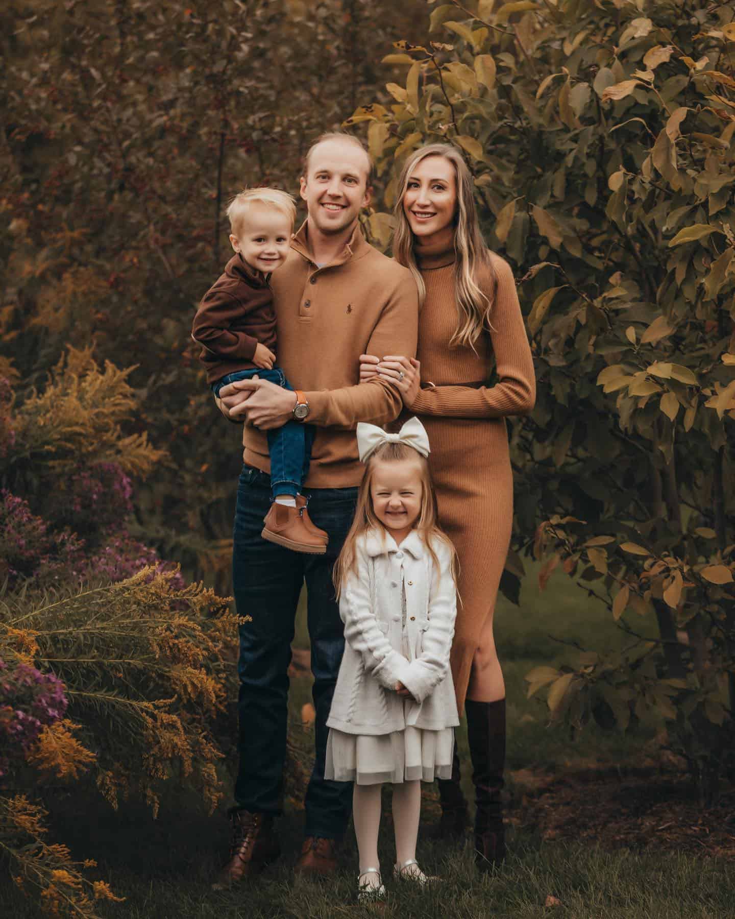 An outdoor family photoshoot with a family of four wearing brown, white, and denim blue clothes