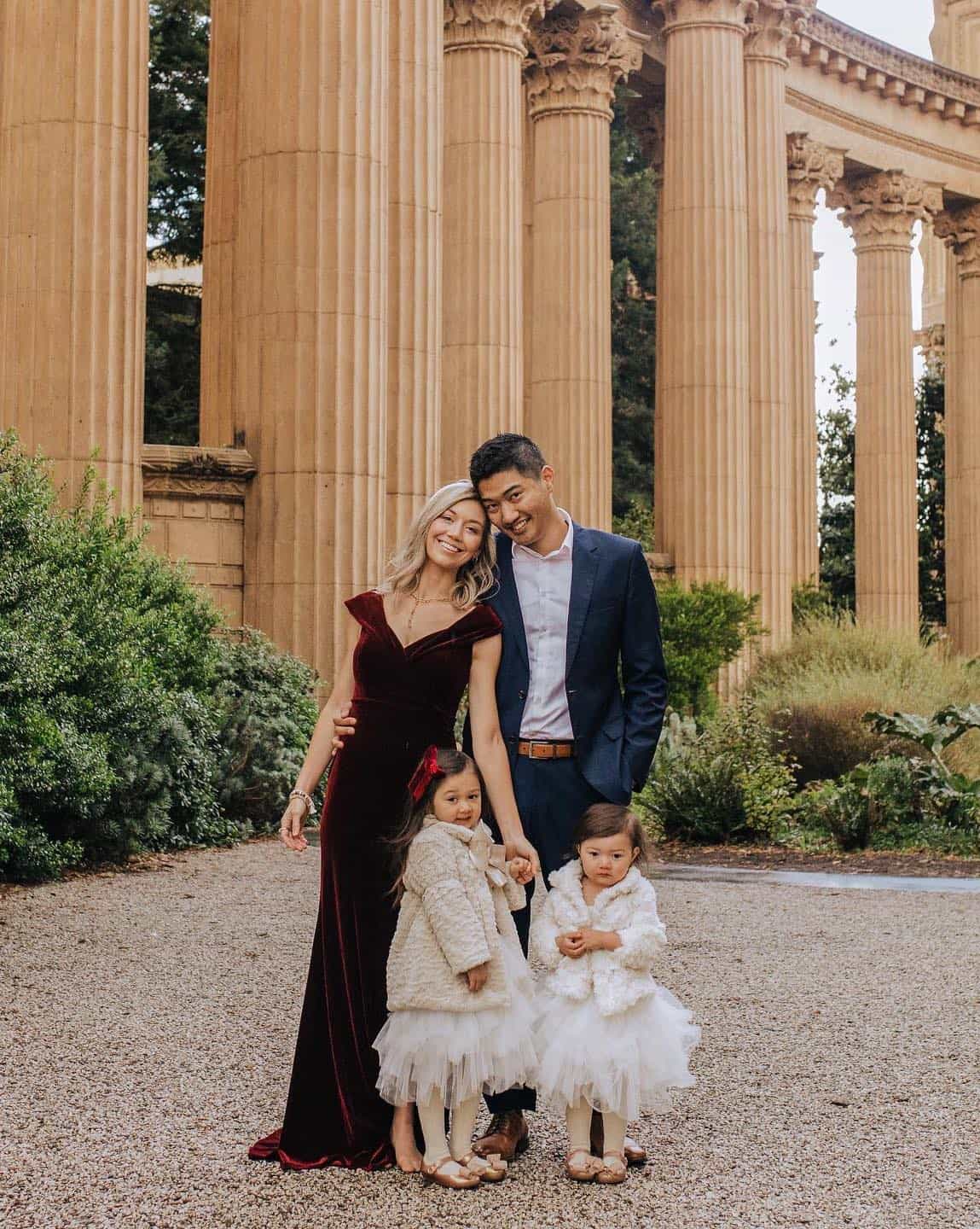 A family photo with a family of four wearing red and white dresses and a navy suit