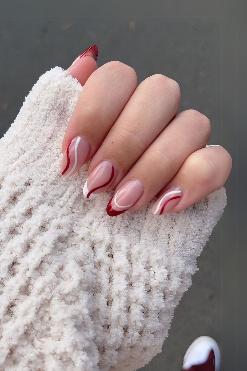 Nude nails with red and white tips and swirls