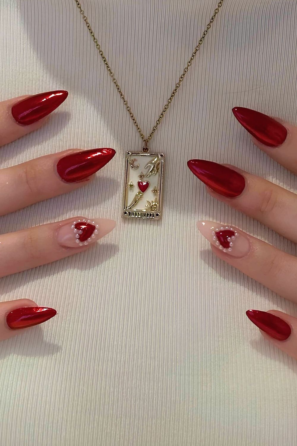 Red chrome nails with heart and pearl accents