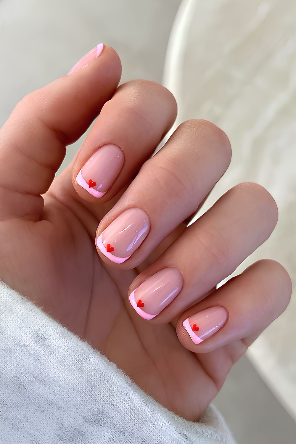 Thin pink French nails with red hearts