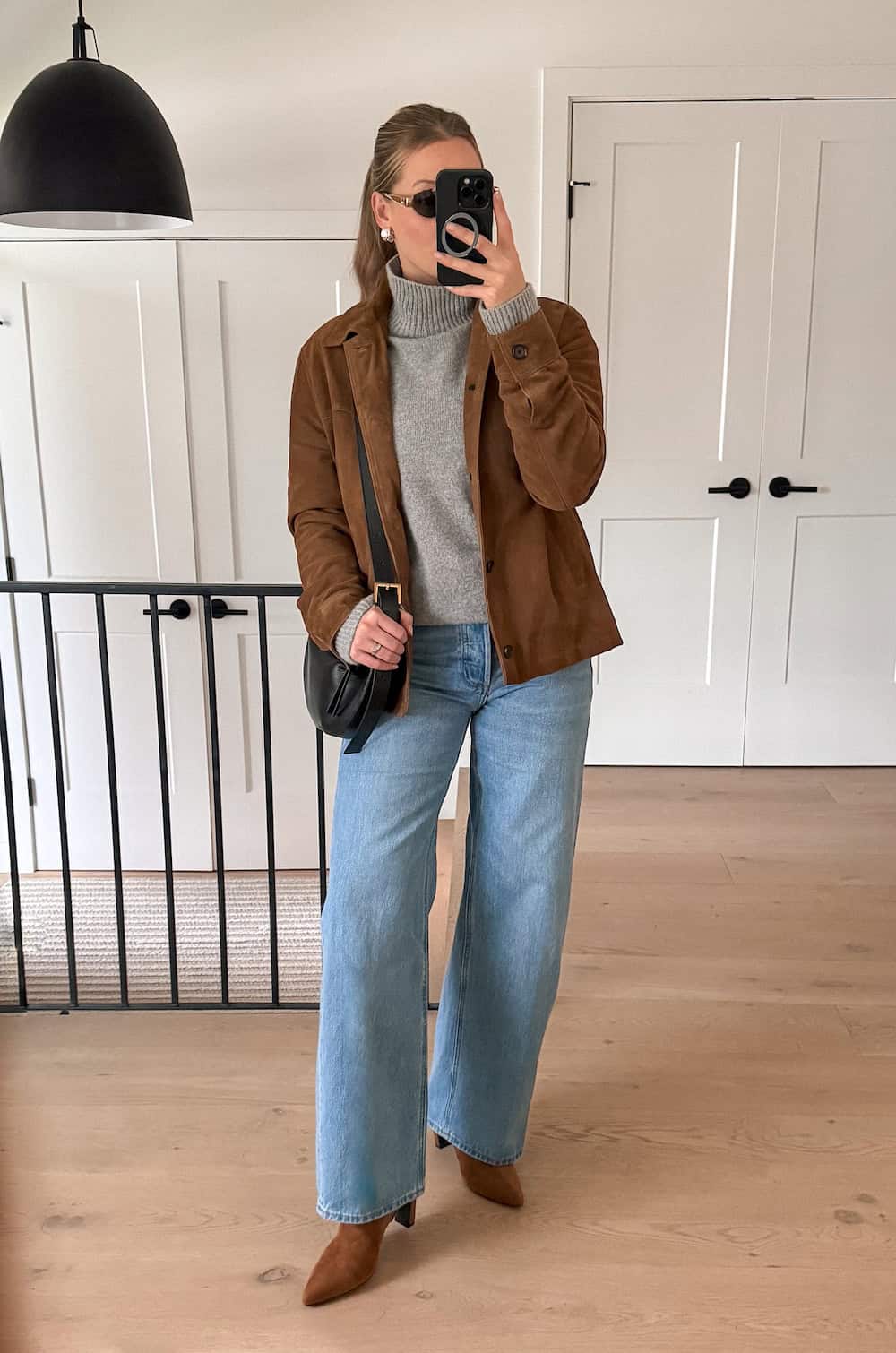 Christal wearing wide leg jeans with a grey sweater and suede booties and jacket.