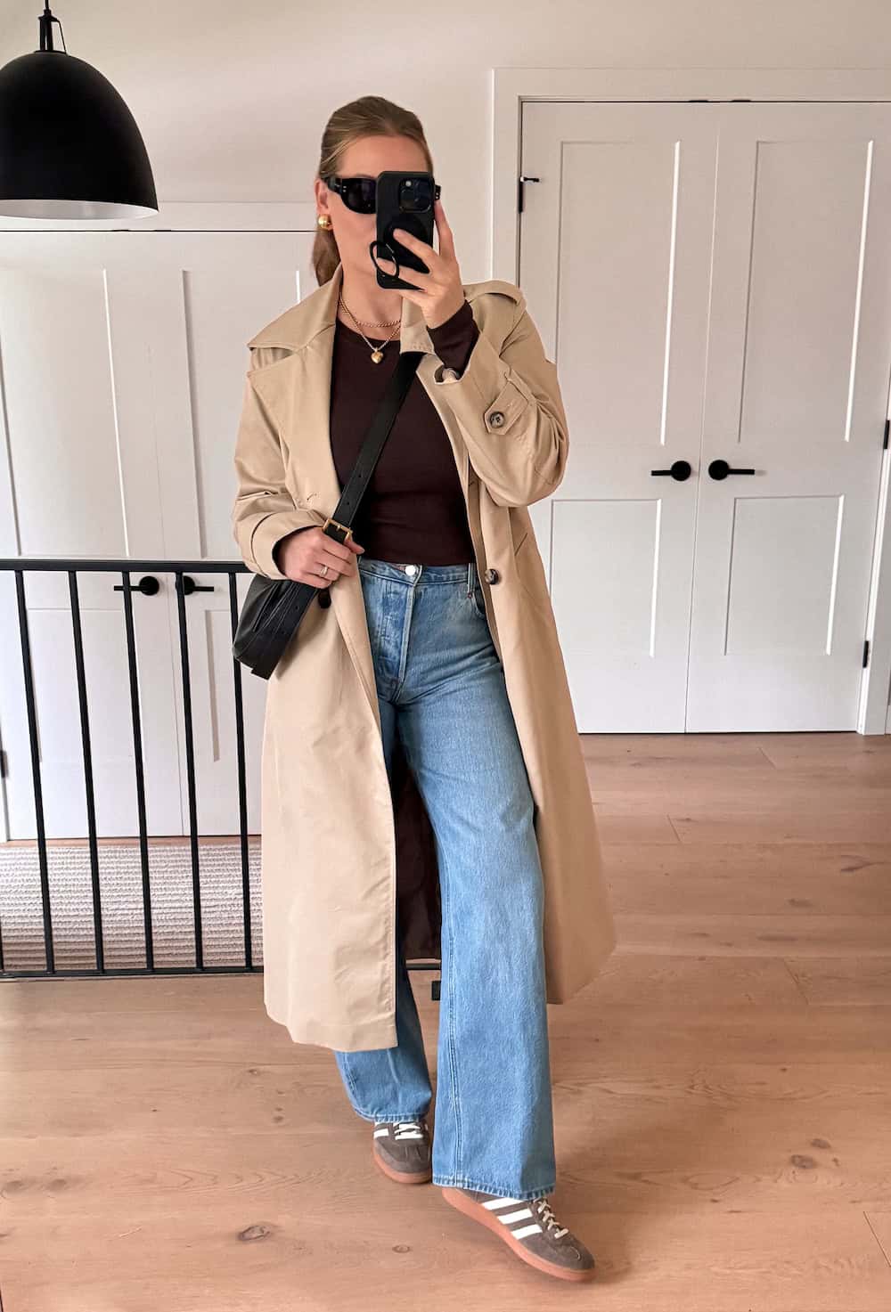 Christal wearing light wash wide leg jeans with sneakers and a trench coat.