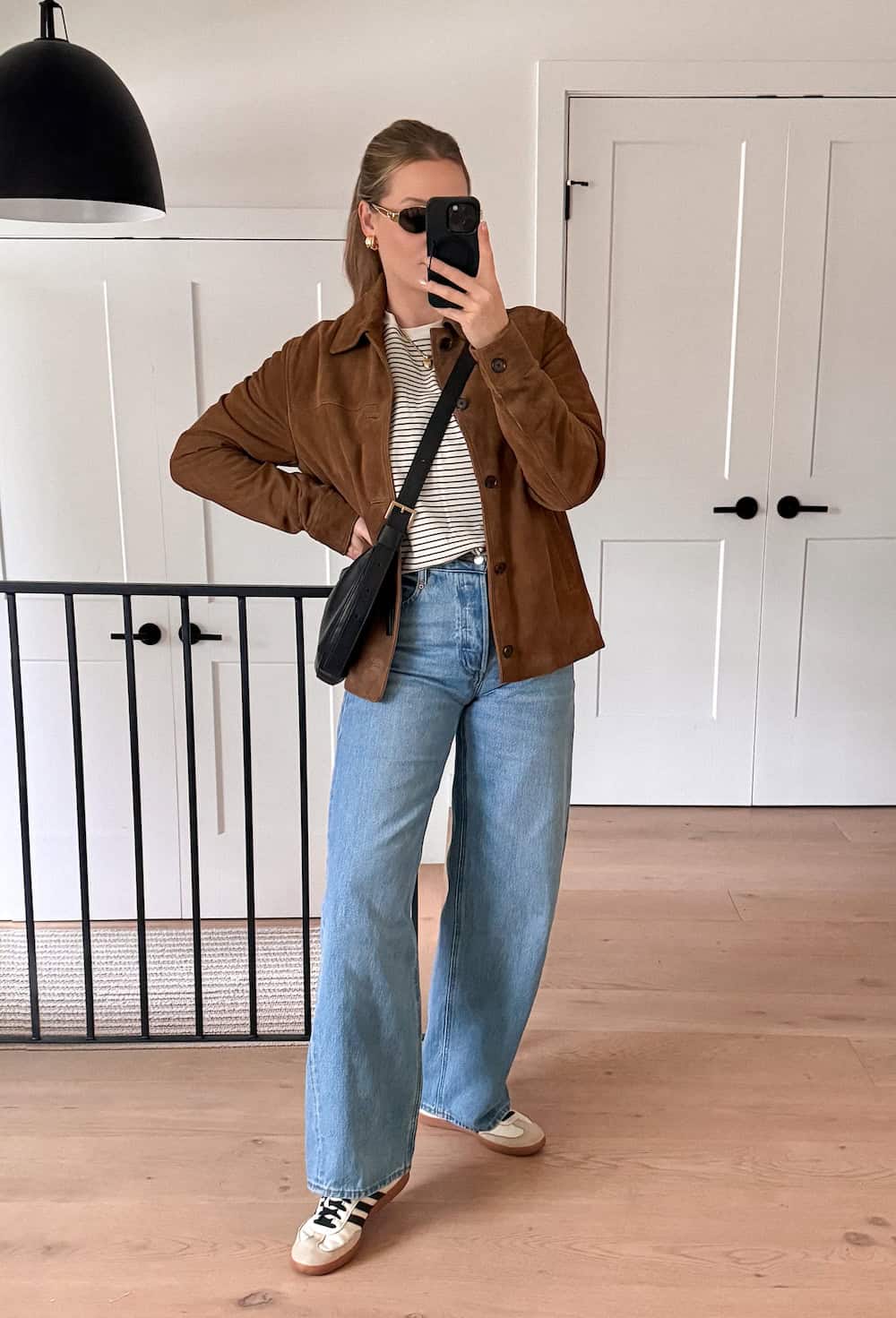 Christal wearing light wash wide leg jeans with a striped shirt and suede jacket.