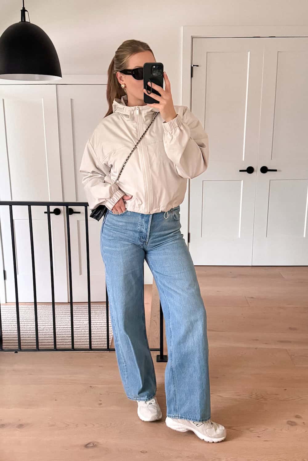 Christal wearing light wash wide leg jeans with a jacket and sneakers.