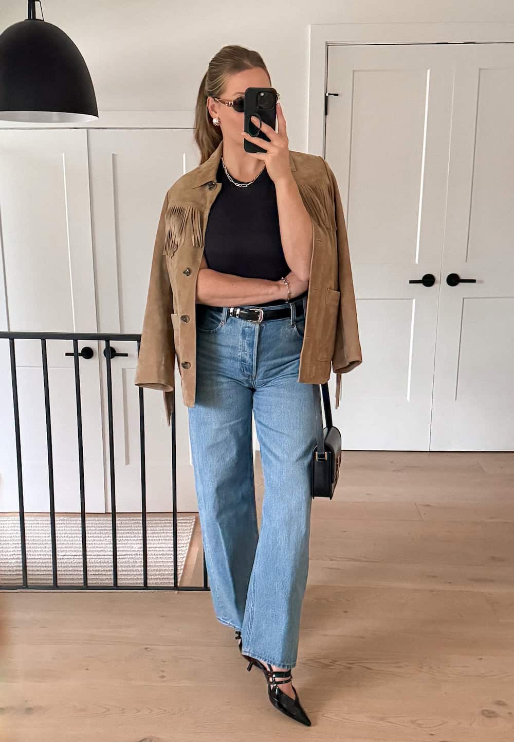 Christal wearing wide leg jeans with a black t-shirt and a suede jacket.