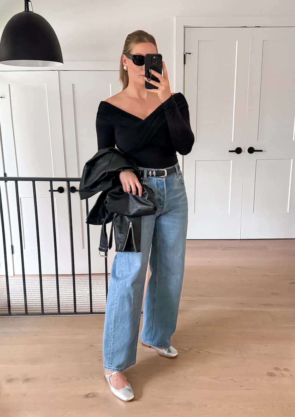 Christal wearing wide leg jeans with a black top and silver ballet flats.