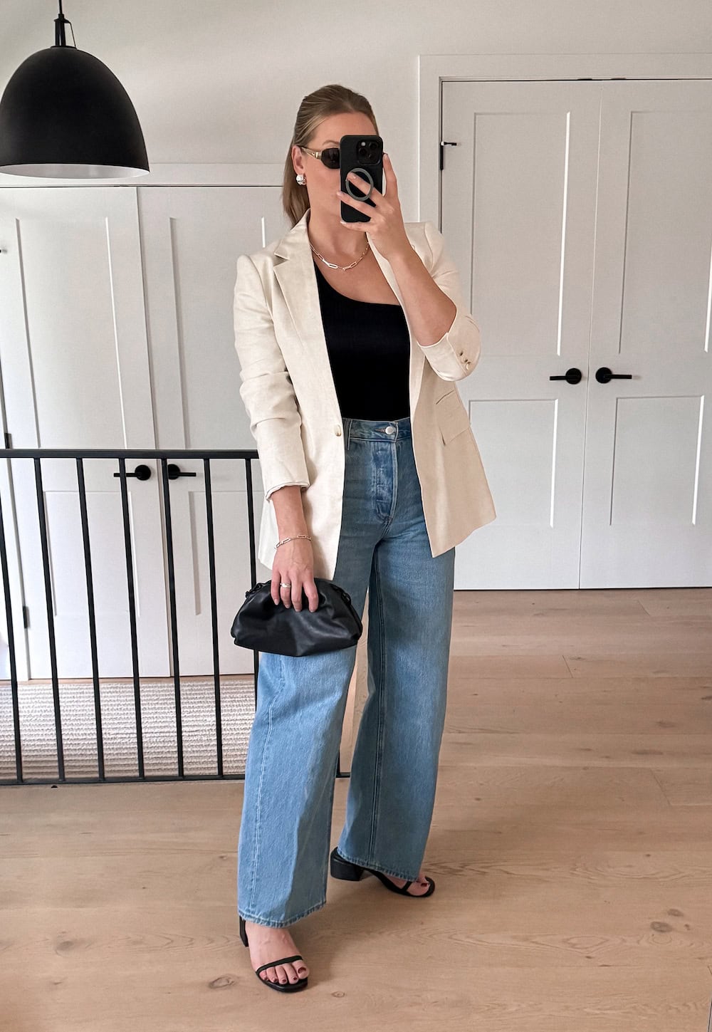 Christal wearing wide leg jeans, an asymmetrical top, and heels.