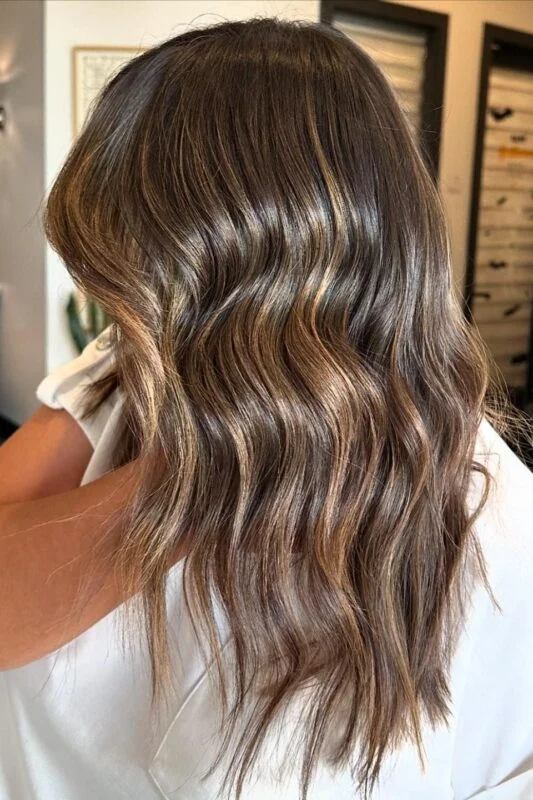 Woman with brown hair and golden caramel highlights.