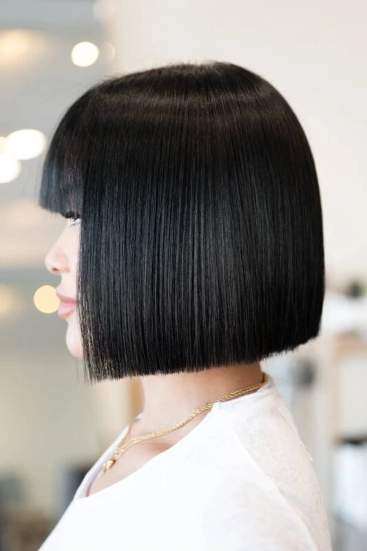 Woman with a chin-length blunt bob haircut featuring blunt bangs.