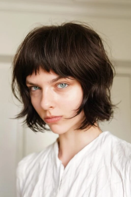 Woman with a chin-length French bob haircut and micro bangs.