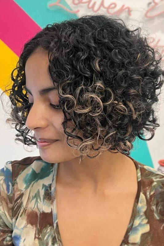 Woman with a chin-length rounded curly bob haircut.