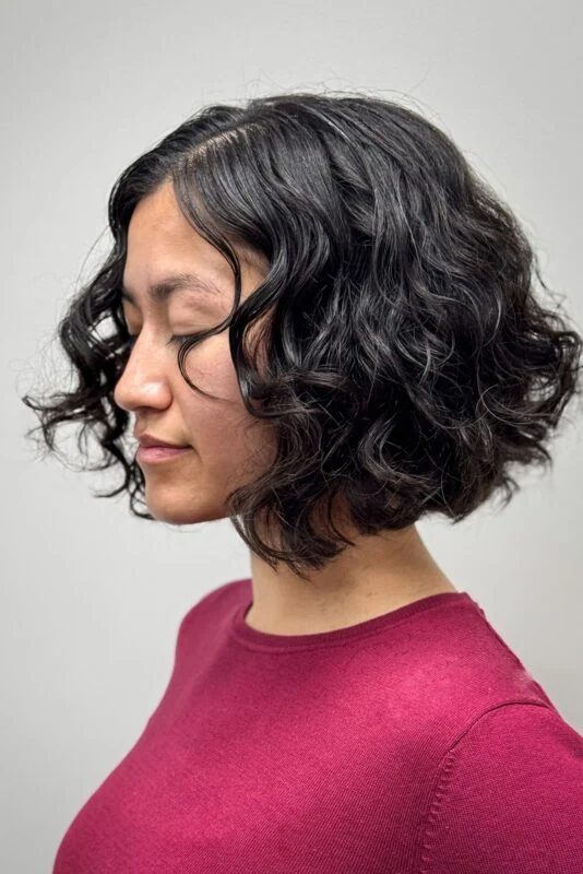 Woman with a chin-length sharp curly bob haircut.