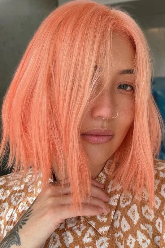 Woman with a coral peach hair color.