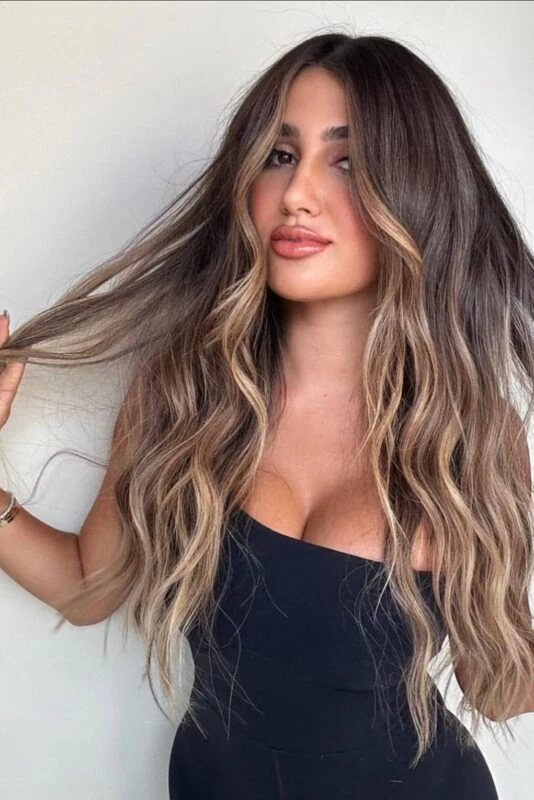 Woman with dimensional walnut brown hair and sun-kissed blonde balayage.