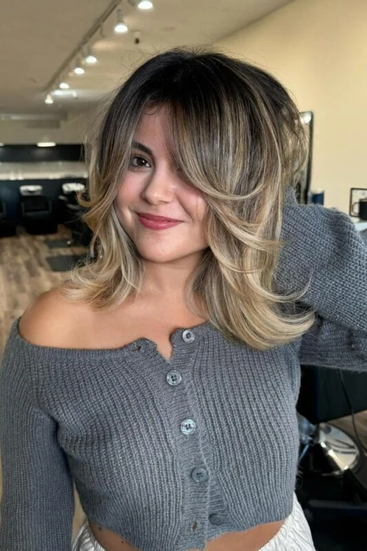 Woman with glowing, lived-in blonde balayage on dark brown hair.