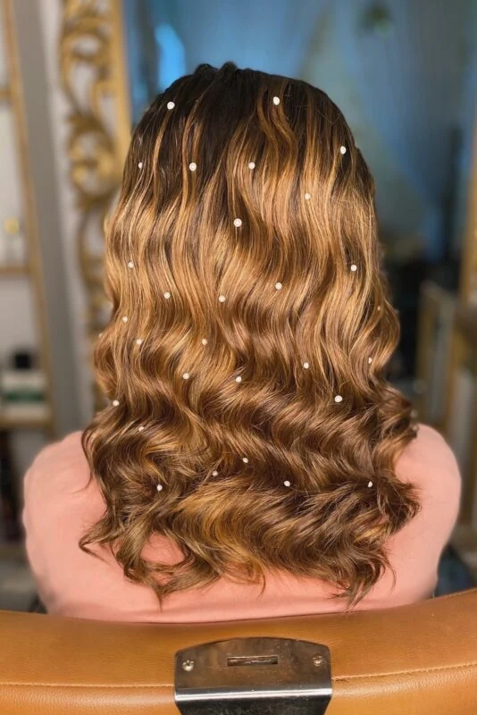 Woman with glamorous waves adorned with pearl embellishments.