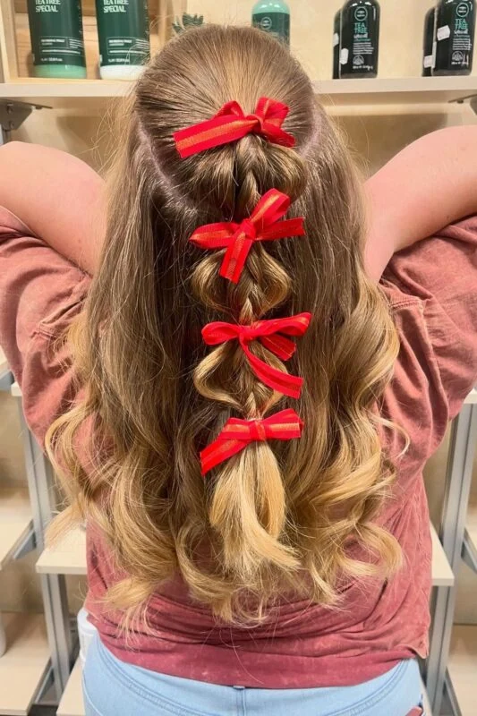 Woman with a half-up braid accented with small red ribbon bows.