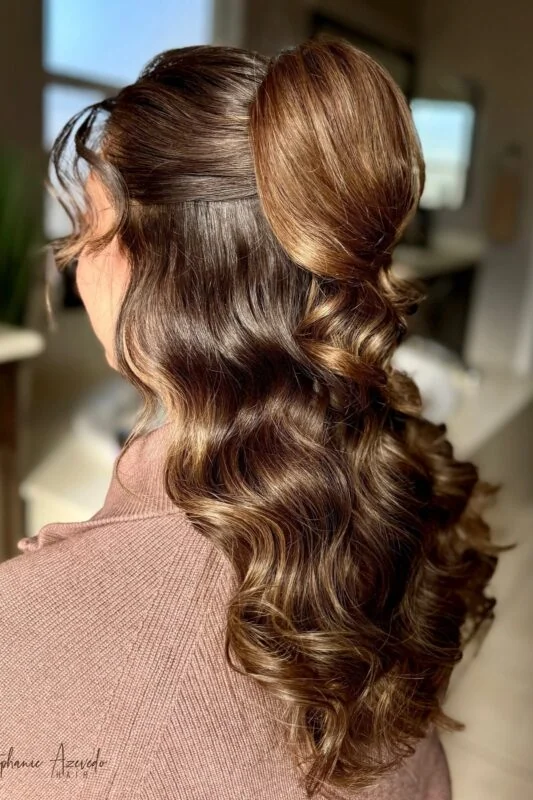 Woman with a half-up, half-down hairstyle featuring a bun and waves.