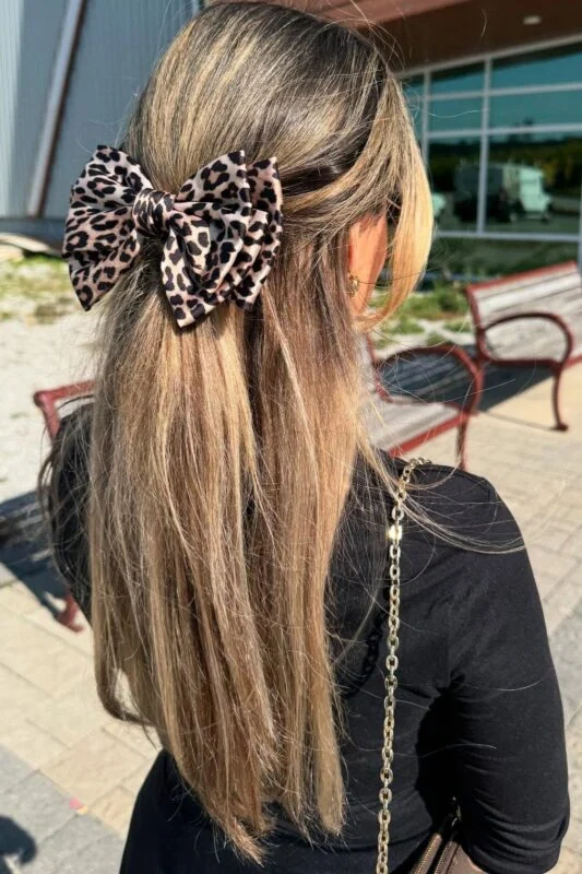 Woman with a sleek half-up, half-down hairstyle with a leopard-print bow.