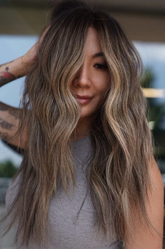 Woman with lived-in honey brown balayage on dark brunette hair.