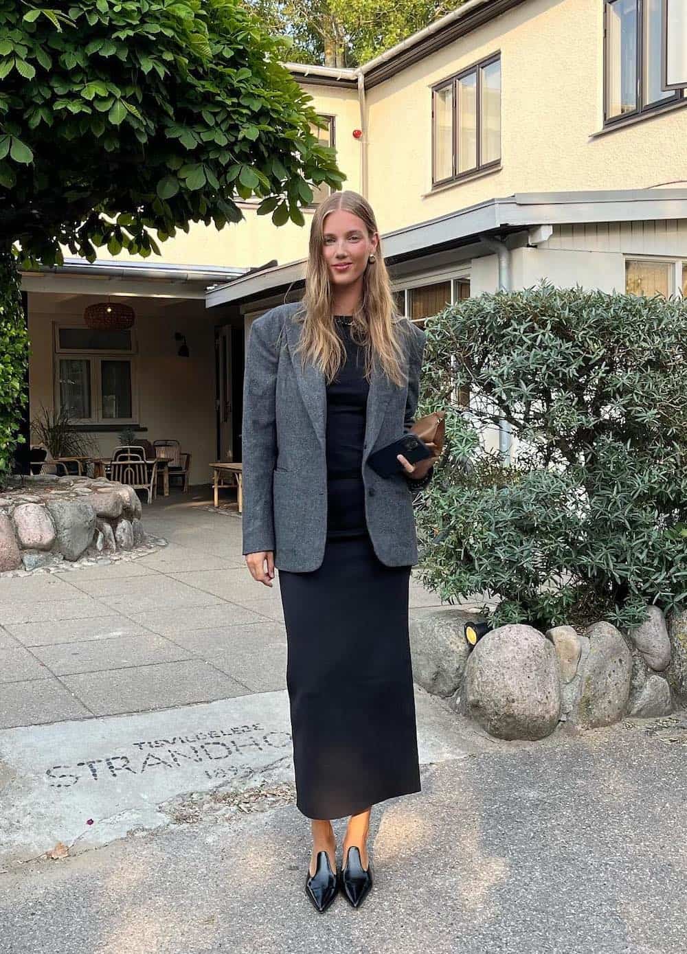 Woman wearing a black maxi skirt with a blazer and heels.