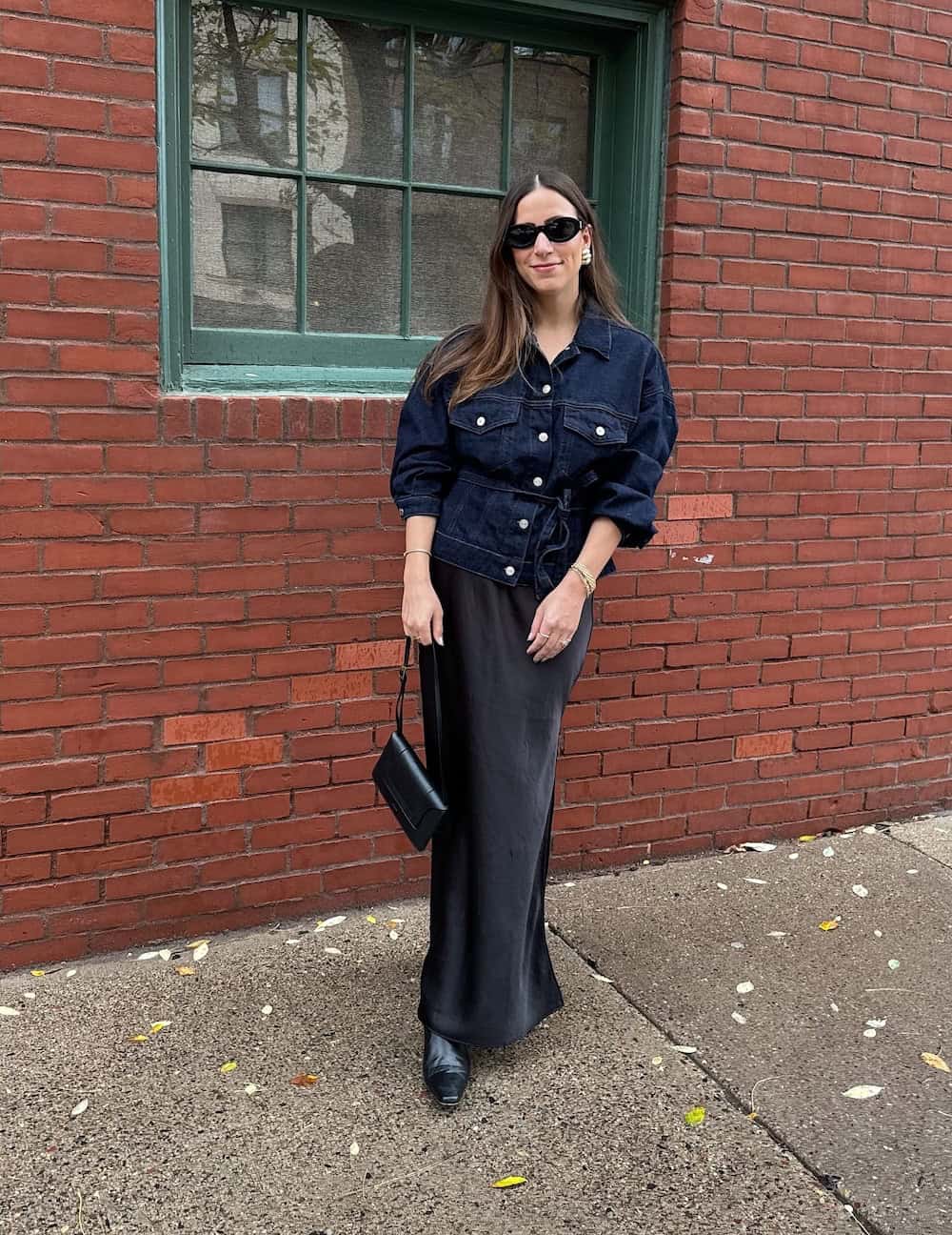 Woman wearing a black maxi skirt with a black button up top.