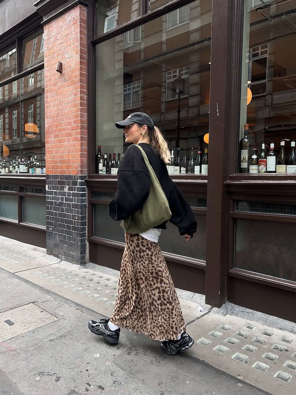 Woman wearing an animal print maxi skirt with a sweater and sneakers.