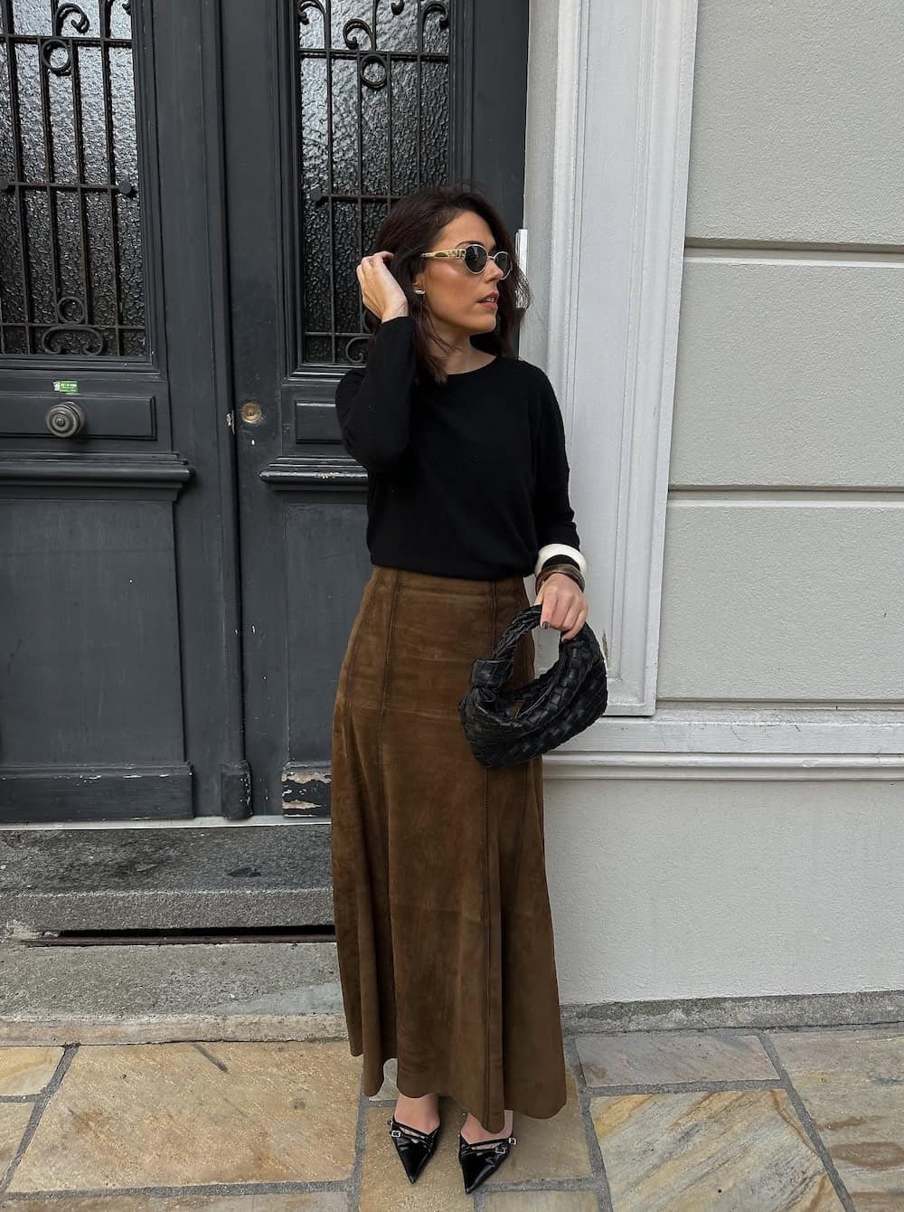 Woman wearing a brown silk maxi skirt with a black sweater and heels.