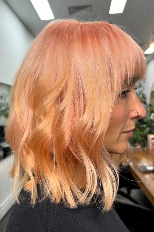 Woman with a neon peach hair color.