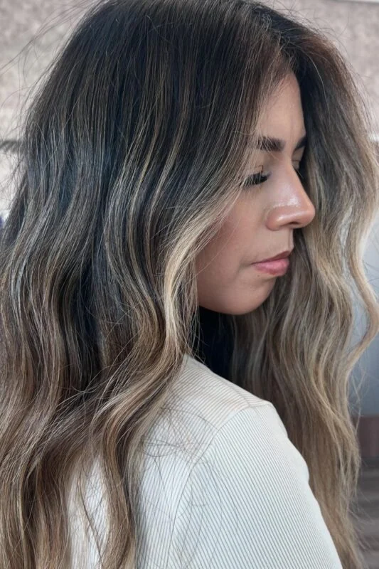 Woman with soft beige and ashy balayage on medium brunette hair.