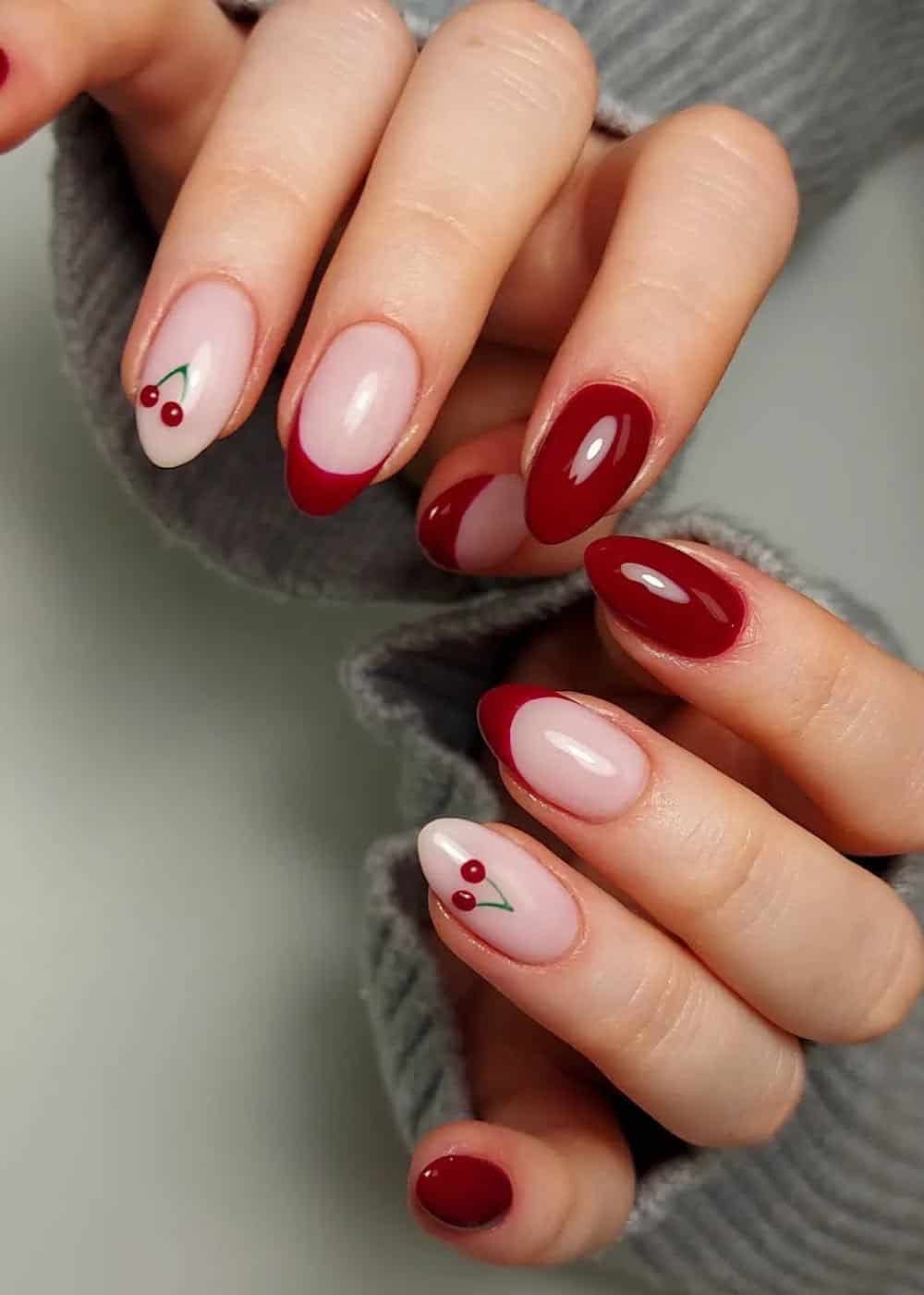 almond nails with red tips, cherry art, and solid nails