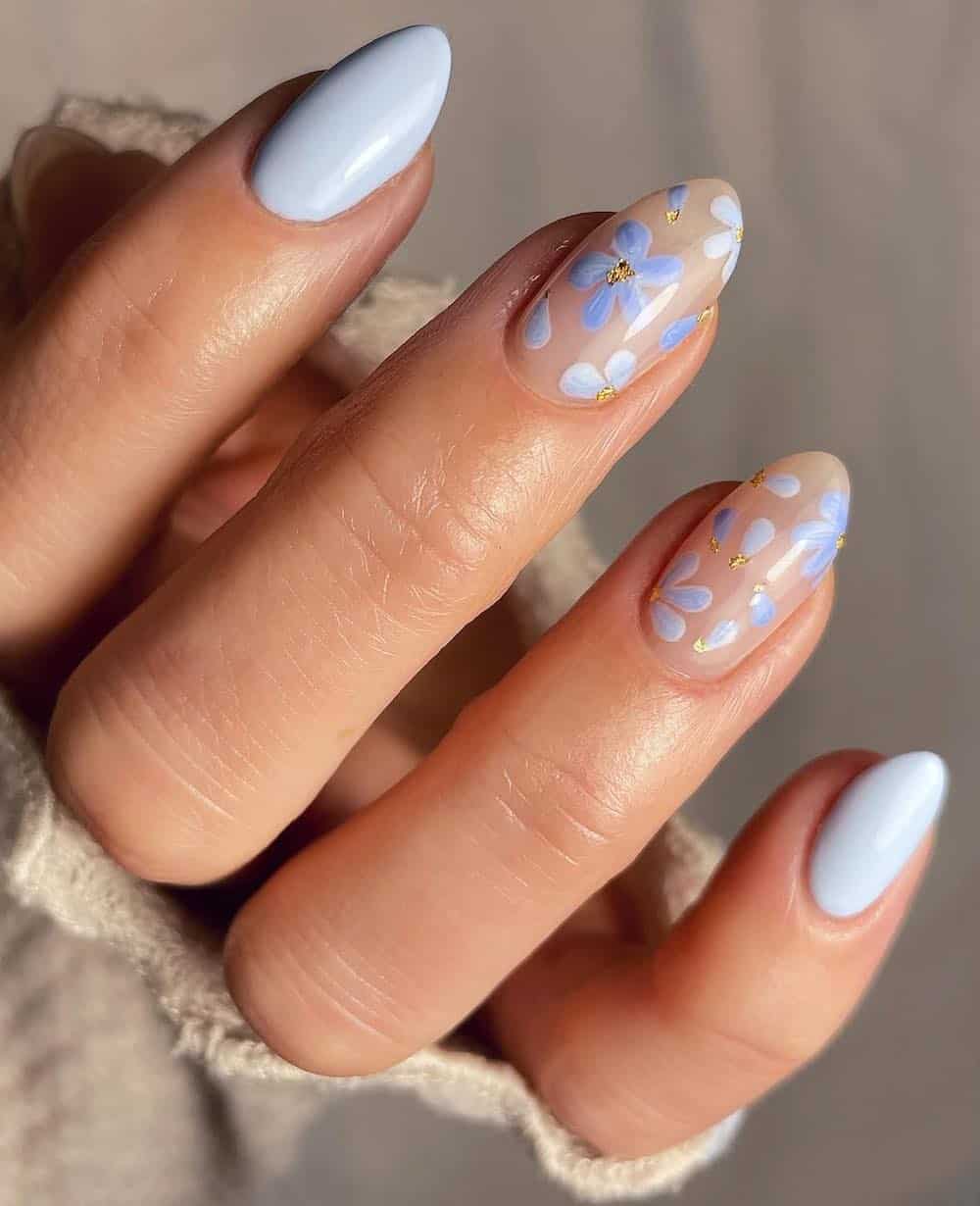 short almond nails with light blue polish and nude accent nails with blue flowers