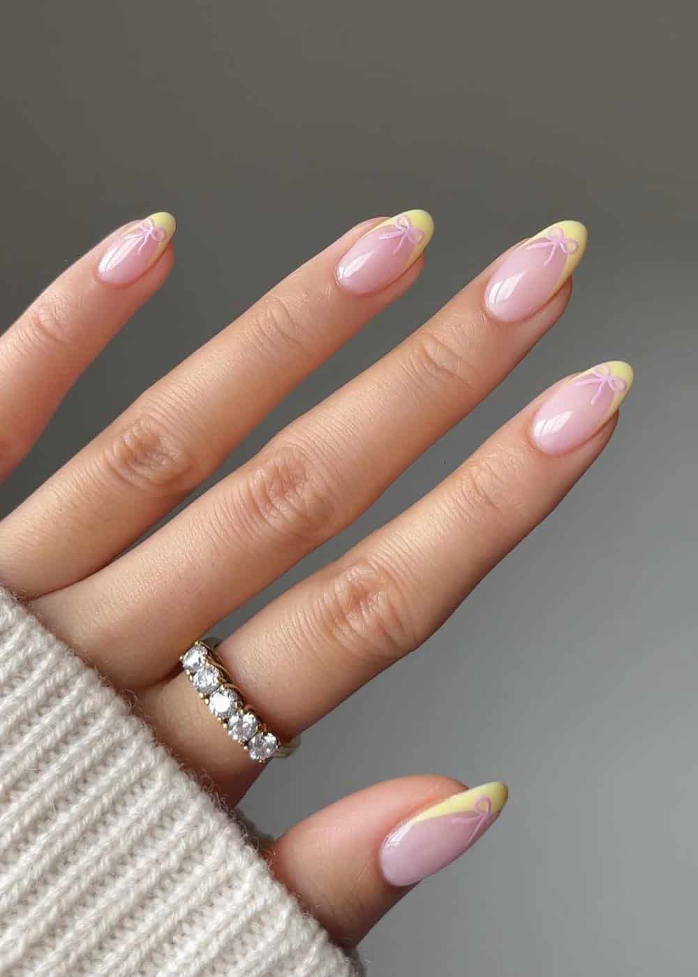 nude almond nails with yellow tips and pink bows