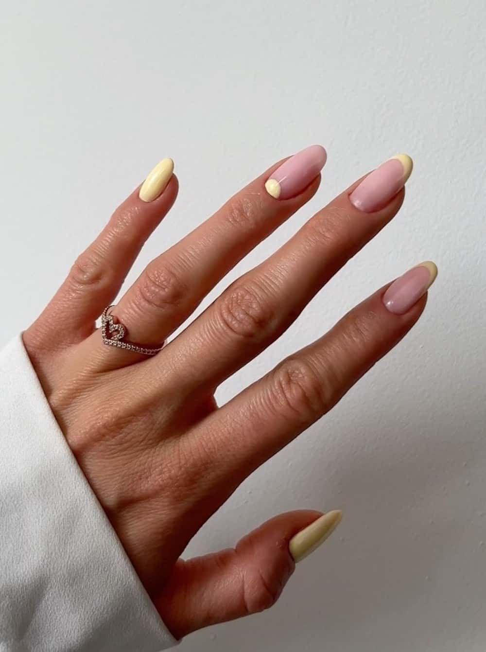 medium nude nails with yellow polish, tips, and reverse french tips