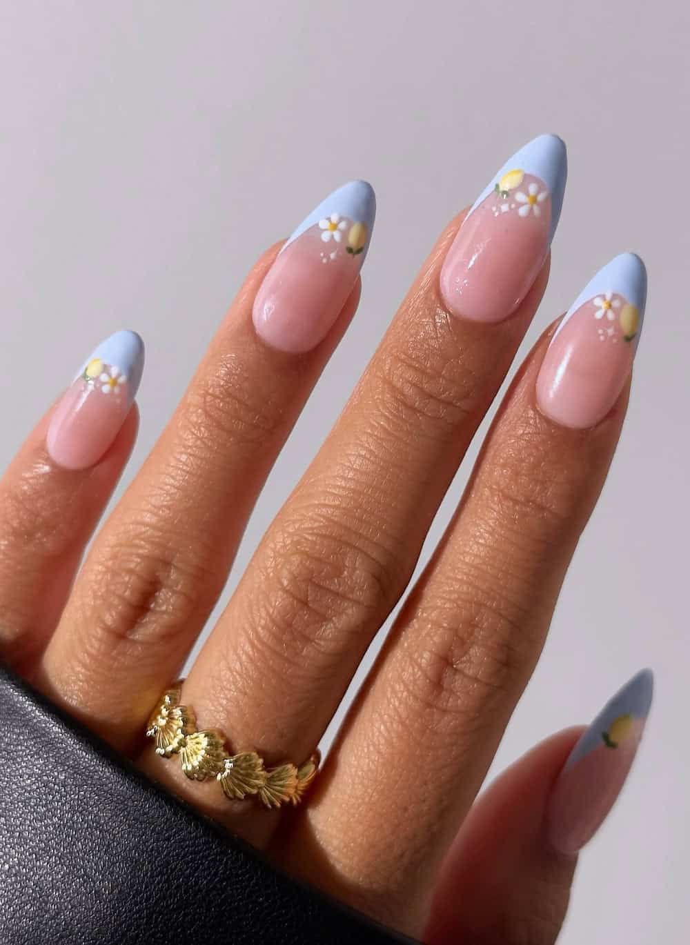 long nude almond nails with light blue tips and lemons and white flowers