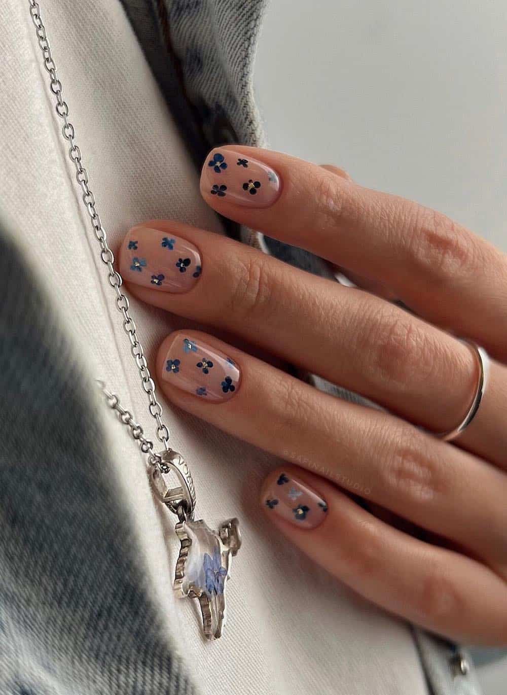 short nude nails with blue and gold flowers