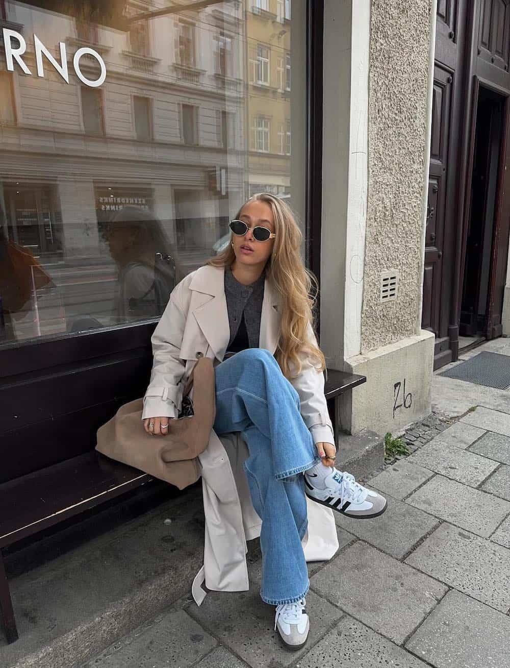 Woman wearing jeans with sneakers and a cardigan.