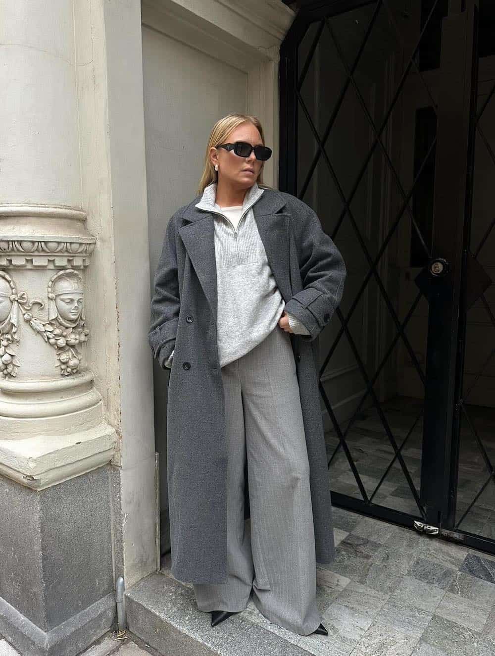 Woman wearing baggy trousers with an oversized sweater and a long wool coat.