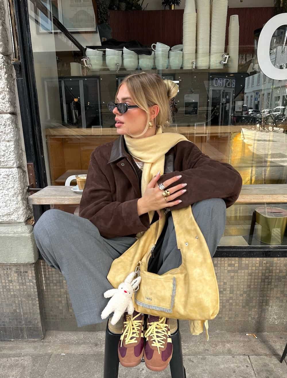 Woman wearing trousers, sneakers and a suede jacket.