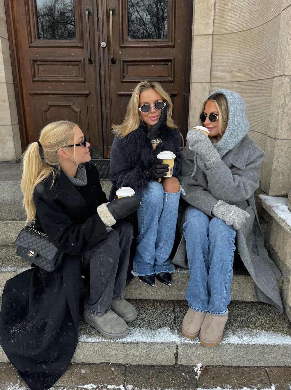 Three women wearing jeans, boots and long boats.