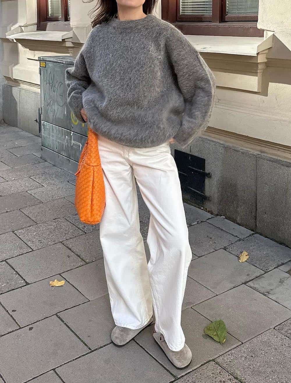 Woman wearing white jeans, Birkenstocks and an eyelash sweater.