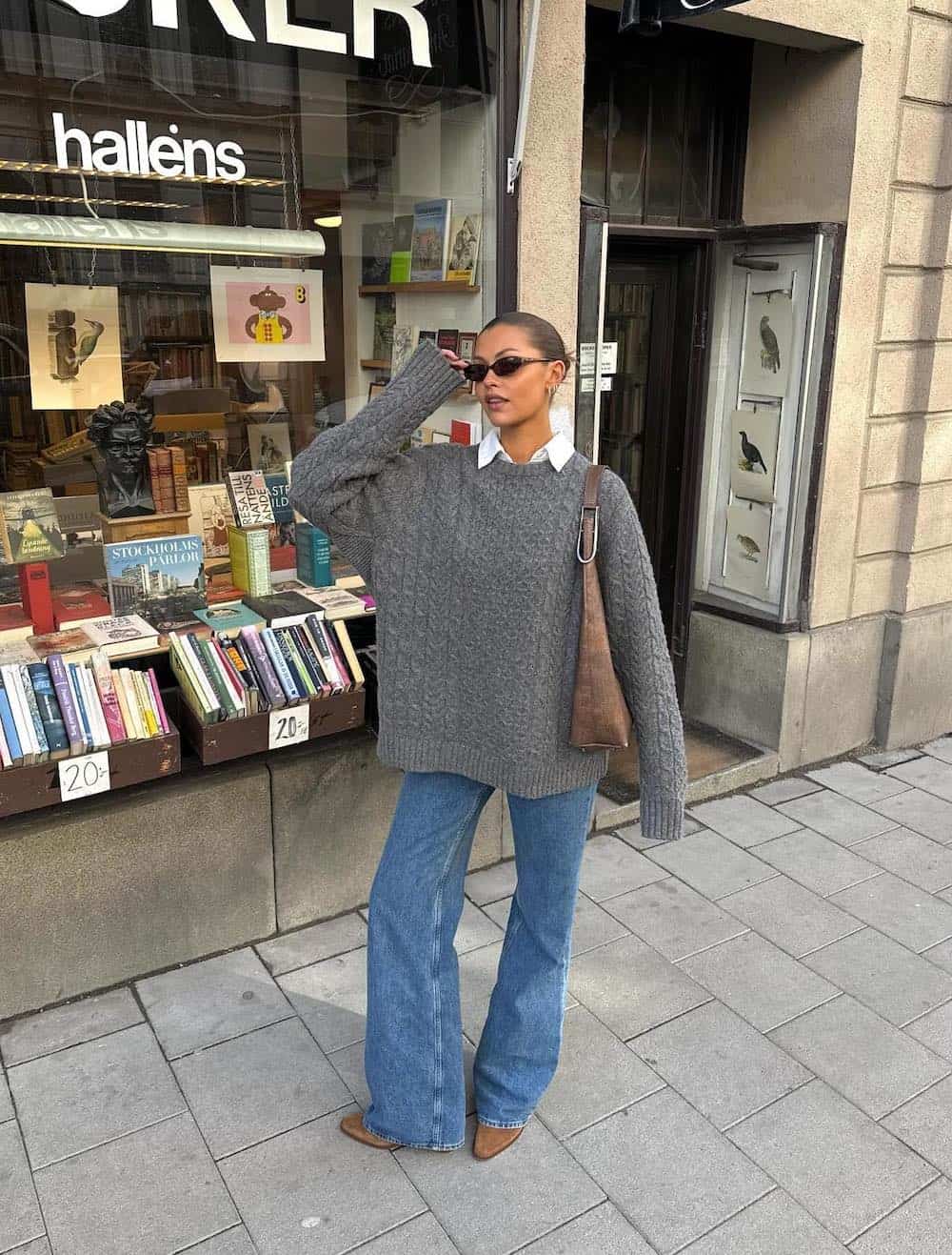 Woman wearing jeans, booties, a button down and an oversized sweater.