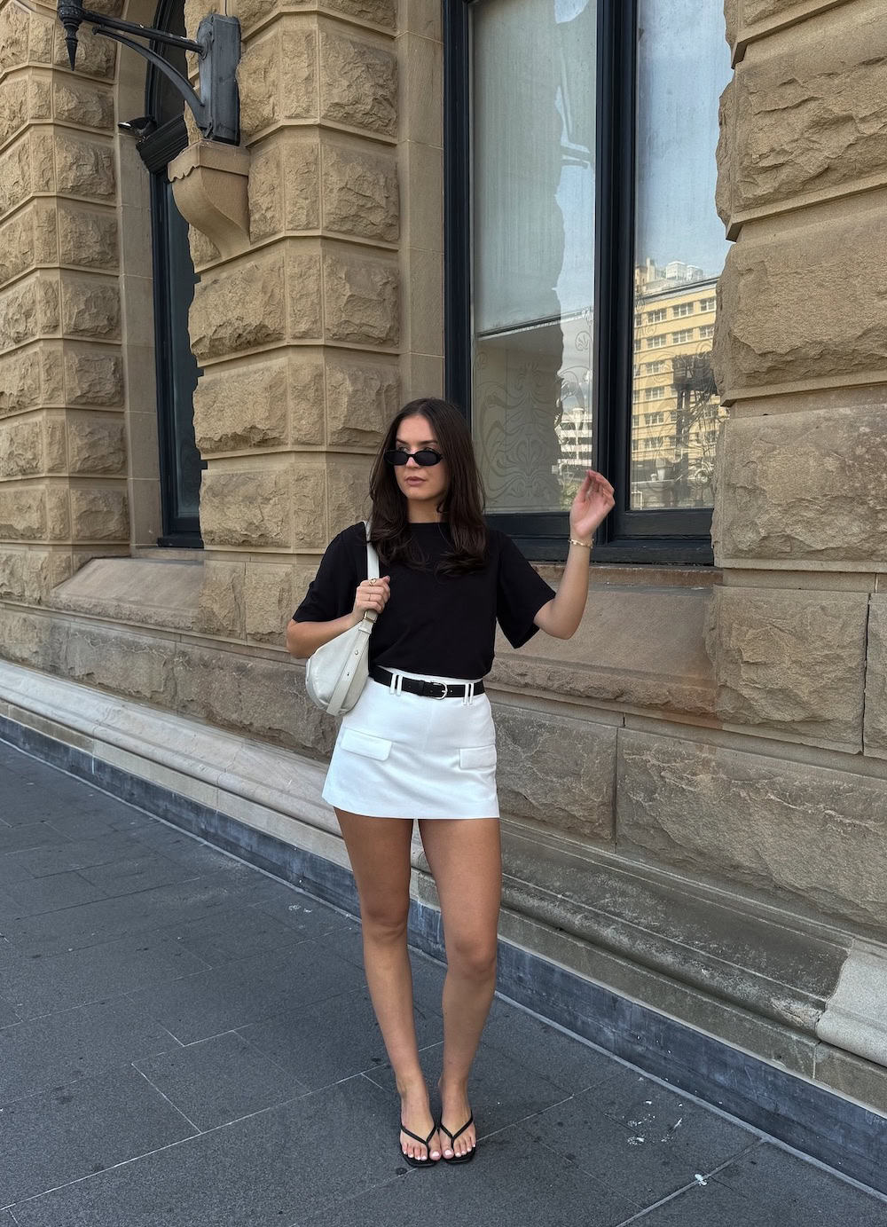 Woman wearing a white shirt with a black t-shirt and black sandals.