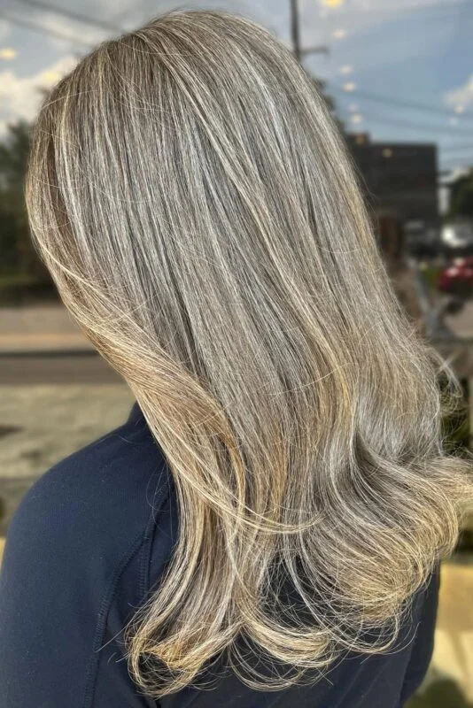 Warm blonde highlights blending seamlessly to hide gray in dark hair.