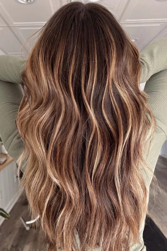 Woman with warm caramel balayage on a dark brown base.