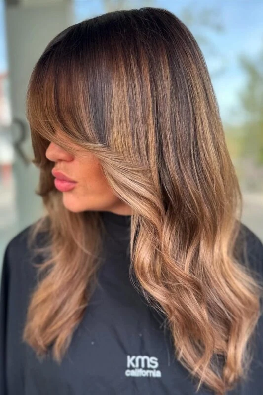 Woman with warm caramel balayage on a dark brunette base.