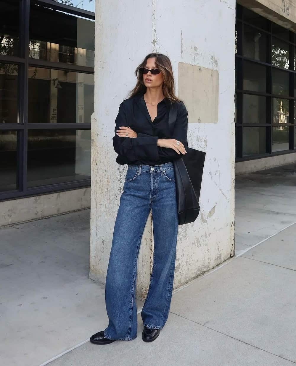 Woman wearing dark wash wide leg jeans and a black button down.