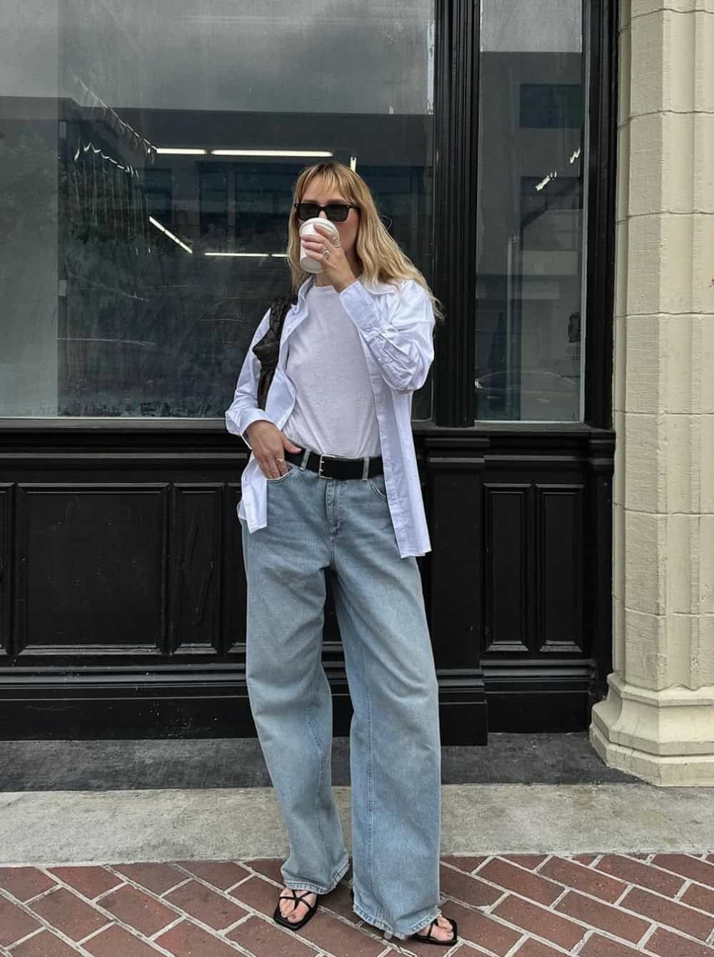 Woman wearing light wash wide leg jeans with a t-shirt and a button down.