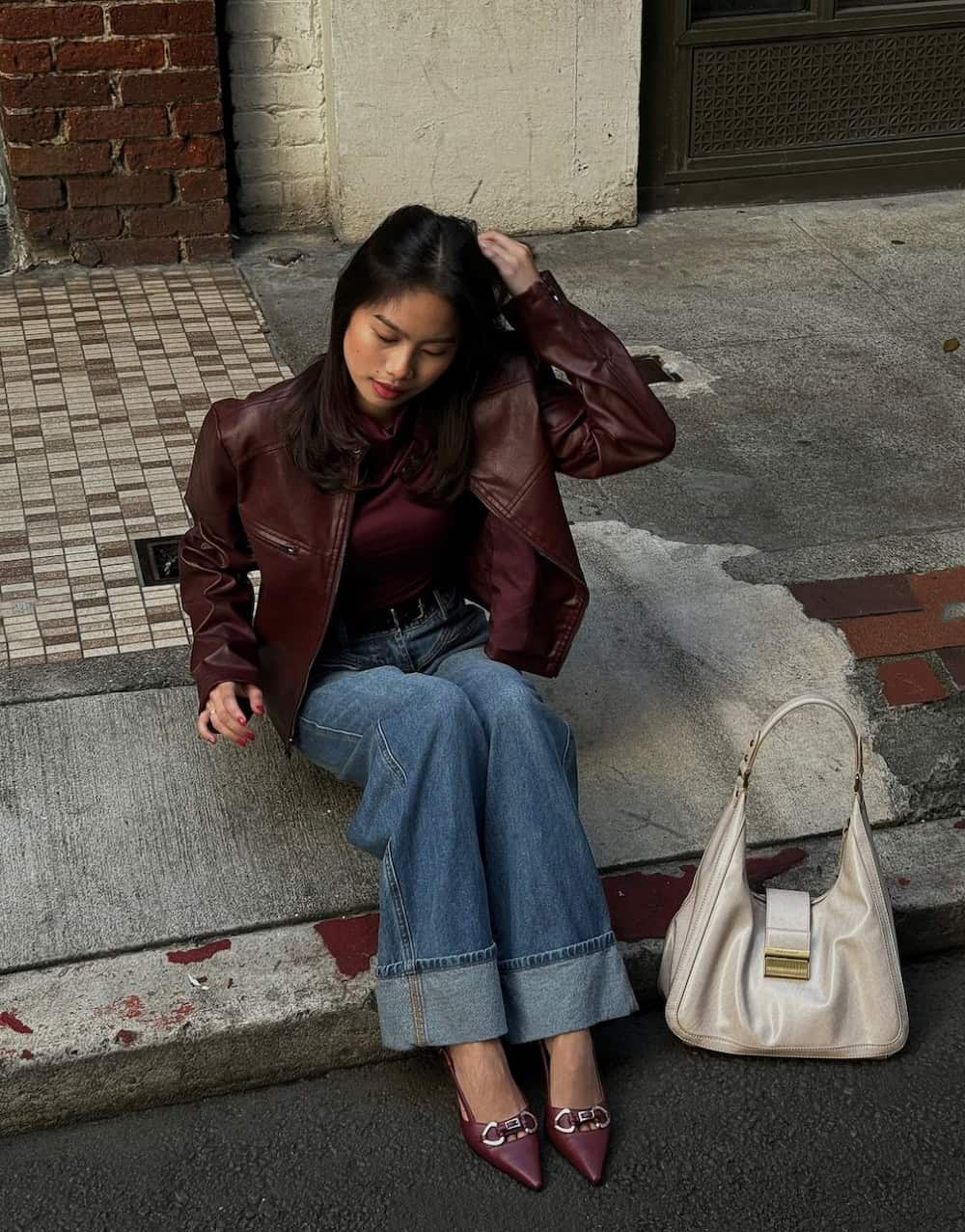 Woman wearing cuffed wide leg jeans with burgundy shoe, shirt and jacket.